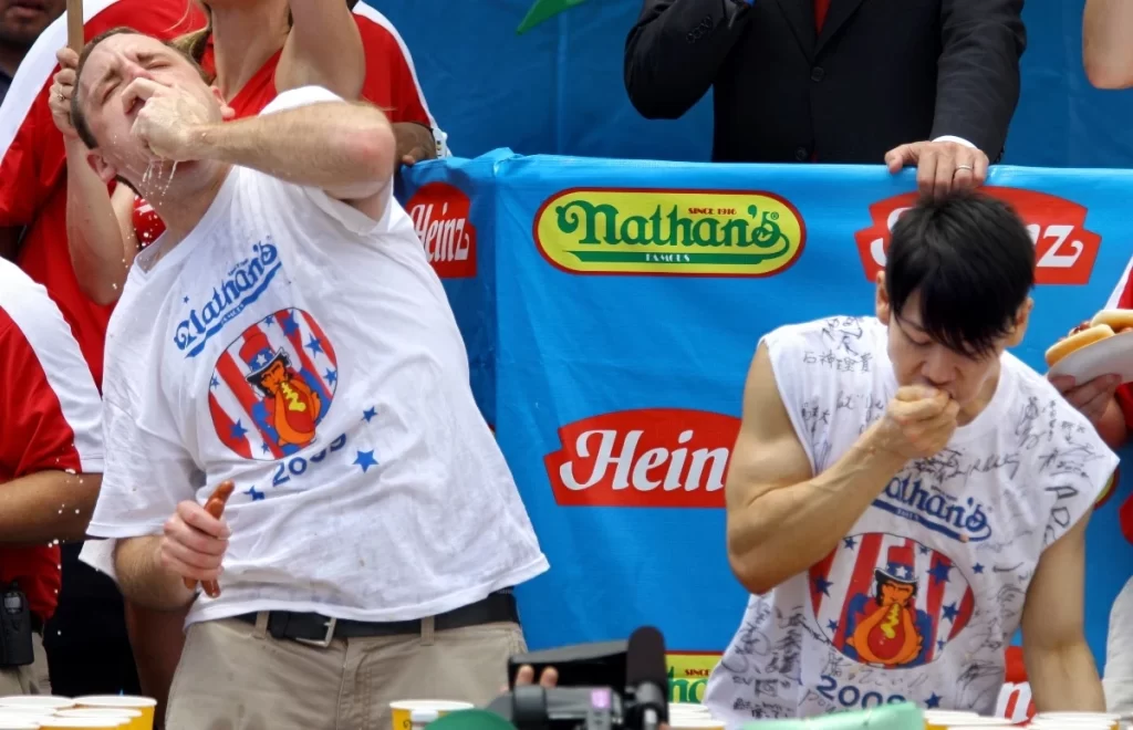 Joey Chestnut (left) and Takeru Kobayashi compete at Nathan’s Famous International Hot Dog Eating Contest on July 4, 2009. The 2009 event was the last time the two competitive eating superstars went head-to-head, but a rematch is scheduled for this Labor Day in a live event to air on Netflix. (Image: AP)